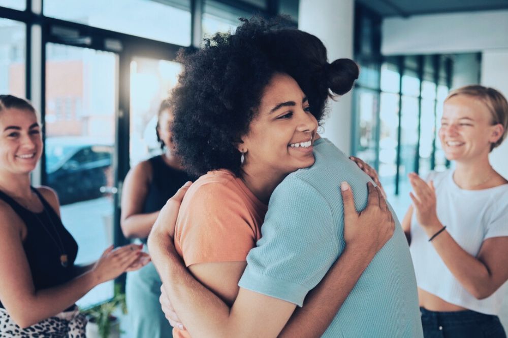 women hugging after group therapy