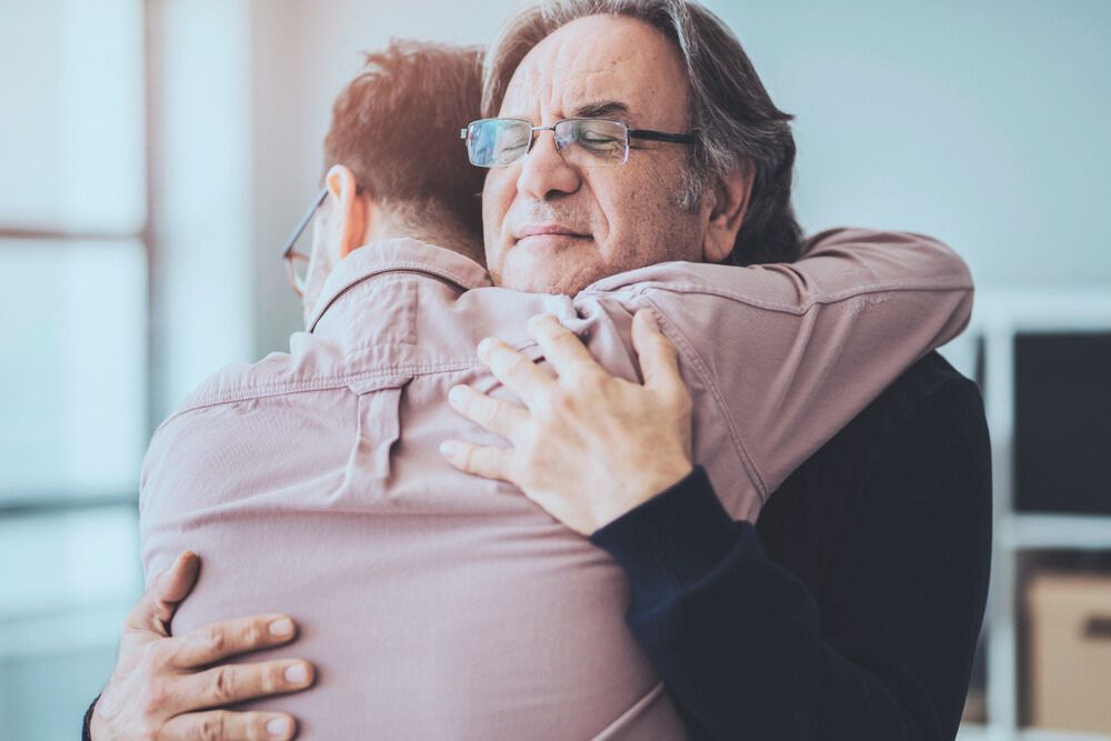 man hugging son after addiction treatment